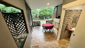 A patio area with a table and chairs, a sink, and a stone wall. - Chambre d'hôte 10 minutes from the Vai'are wharf. (Windward Islands)