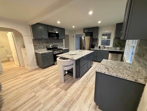 Eine moderne Küche mit dunklen Schränken, Granit-Arbeitsplatten und Edelstahlgeräten.