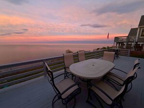 Eine Terrasse mit Tisch und Stühlen mit Blick auf ein Gewässer bei Sonnenuntergang.