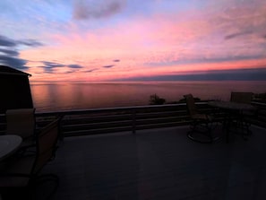 Terassi, jossa on ulkona oleva oleskelualue, josta avautuu näkymä vesistöön auringonlaskun aikaan.