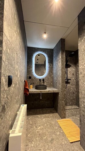 Ein modernes Badezimmer mit rundem Spiegel, Waschbecken und Dusche.