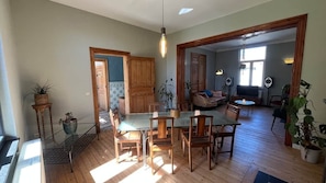 Un grand espace de vie comprenant une table à manger, des chaises et un canapé. On y trouve également des plantes en pot et une porte en bois.
