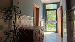 Un pasillo con piso estampado, un banco grande de madera, una planta en maceta y una lámpara en el techo.