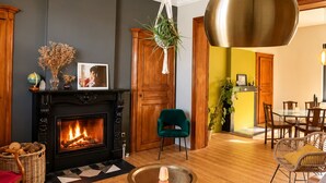 Una sala de estar con chimenea, una lámpara colgante, un comedor y un sofá.