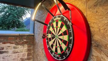 A dartboard mounted on a wooden wall with a window in the background.