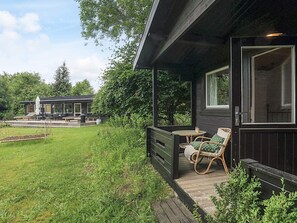 A wooden cabin with a porch, a dining area, and a separate building with outdoor seating. - 4 Star Holiday Home in Tisvildeleje (Tisvildeleje)