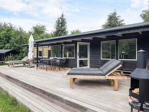 A wooden deck with outdoor furniture, a grill, and a covered seating area. - 4 Star Holiday Home in Tisvildeleje (Tisvildeleje)