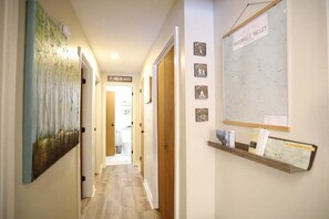 A hallway with a painting, a map, and a sign indicating a hiking trail. - Pet Friendly Waterville Valley Condo close to Town (Waterville Valley)