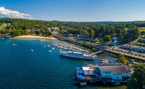 Une ville côtière dotée d’un port de plaisance, de bateaux et d’un grand bâtiment blanc surmonté d’un toit bleu.