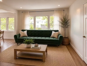 Una sala de estar con un sofá verde, una mesa de centro de madera y una planta en maceta.