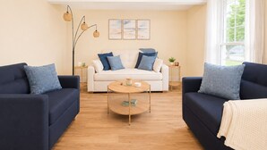 A modern living room with a white sofa, two dark sofas, a round coffee table, and a floor lamp. - Lake Erie Retreat (Dunkirk)
