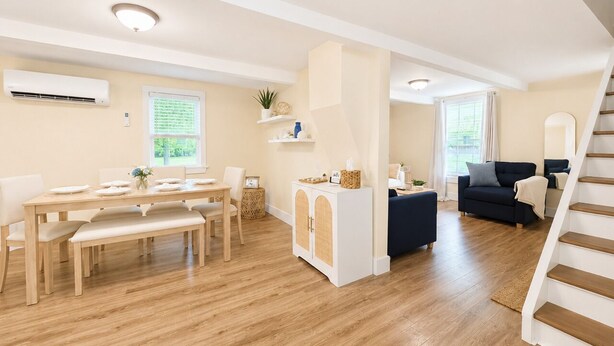 A modern living room with a dining table, sofa, and staircase. - Lake Erie Retreat (Dunkirk)
