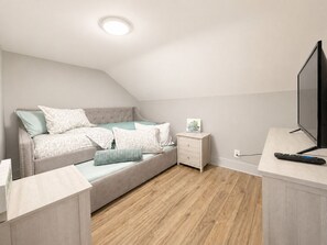 Ein Schlafzimmer mit Bett, Nachttisch, Fernseher und Holzboden.