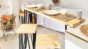 A dining area with a long table, chairs, and hanging wicker pendant lights.