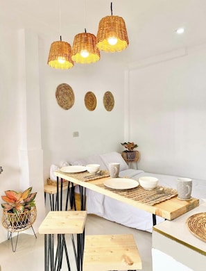 Un espace repas avec une longue table, des chaises et des suspensions en osier.