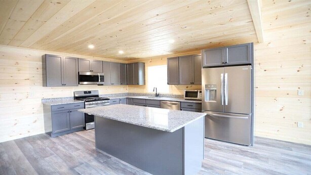 Una cocina moderna con armarios grises, electrodomésticos de acero inoxidable y una isla con encimera de granito.