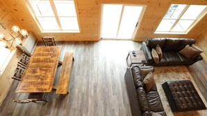 Un interior de madera con una mesa de comedor, sofá y un amplio ventanal.