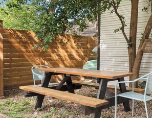 Una mesa de picnic de madera con bancos, rodeada por una valla de madera y un árbol.