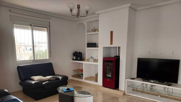 Ett vardagsrum med en soffa, ett soffbord, en tv och en röd apparat.
