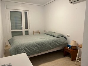 A single bed with a patterned bedspread, a bedside table with a lamp, and a chair. - House with a pool and air conditioning (Mazarrón)