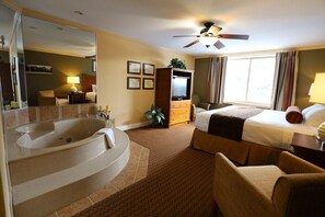 Ein Hotelzimmer mit einer großen Badewanne, einem Bett, einem Fernseher und einem Deckenventilator.