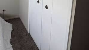 A white closet with two doors and a small shelf, carpeted floor, and a power outlet on the wall. - Cozy 1 bedroom in a 2 bedroom apartment in charming Mayfield Heights. (Mayfield Heights)