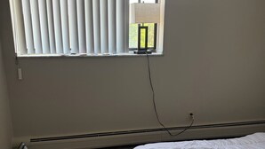 A bedroom with a large window, a standing heater, and a bed. - Cozy 1 bedroom in a 2 bedroom apartment in charming Mayfield Heights. (Mayfield Heights)