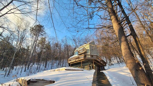 A wooden staircase leading to a multi-level cabin in a snowy forest. - Cozy Retreat in Waterville Estates! RR194E (Campton)