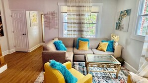 A living room with a sofa, armchairs, a coffee table, and a rug.