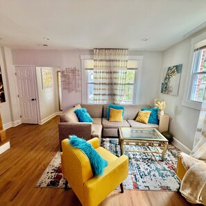A living room with a sofa, armchairs, a coffee table, and a rug.