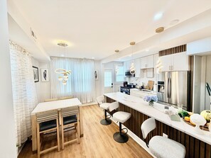 A modern kitchen with a central island, bar stools, and a dining table. - Charming 3-bedroom house in Washington with cool AC breeze (Washington)
