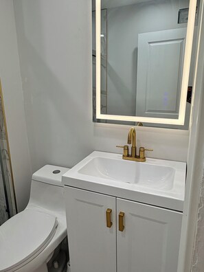 Une salle de bain avec un lavabo blanc, un miroir et des toilettes.