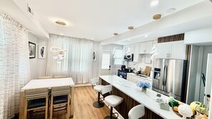 A modern kitchen with white cabinetry, stainless steel appliances, and a marble countertop.