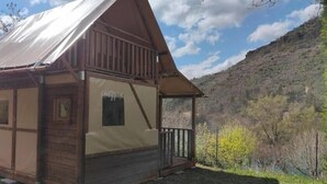 Une cabane avec une façade en bois, une véranda et une vue sur un paysage montagneux.