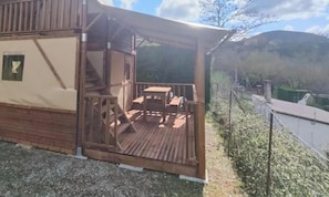 Eine Holzhütte mit einer Terrasse, einer Treppe sowie einem Tisch und Stühlen.