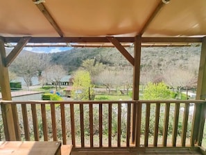 Ein hölzerner Balkon mit Blick auf eine angelegte Grünfläche und ein Gewässer.