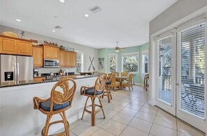 A kitchen with wooden cabinets, stainless steel appliances, and a dining area with wicker chairs.
