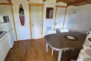 Une pièce avec un plancher en bois, une table à manger avec des chaises, un four à micro-ondes et un réfrigérateur.