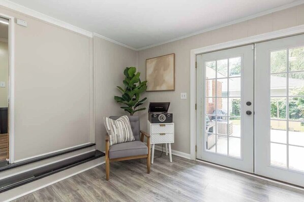 Una habitación con una silla, una planta, un radio y una puerta que da al exterior.
