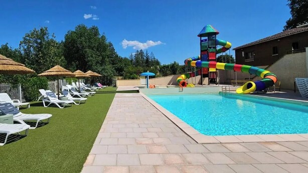 A swimming pool with a colorful slide, sun loungers, and umbrellas. - ZEcamping 3* pataugeoire piscine chalet 29m2 5 pers (Saint-Projet)