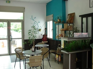 A cafe with wicker chairs, a guitar, and a fish tank. - ZEcamping 3* calme et nature - proche châteaux de la Loire (Savigny-en-Véron)