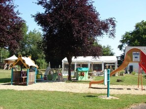 Un parque infantil con estructuras de juego, una zona de estar cubierta y un tobogán.