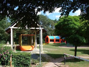 A playground with a swing set, a climbing structure, and a small shelter. - ZEcamping 3* calme et nature - proche châteaux de la Loire (Savigny-en-Véron)
