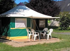 Ein Zelt mit Tisch und Stühlen aufgebaut im Freien.