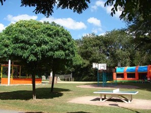 Ein Park mit Basketballplatz, Spielplatz und Picknicktisch.