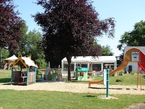 Ein Spielplatz mit Spielgeräten, einer überdachten Sitzgelegenheit und einer Rutsche.