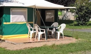 Ein Zelt mit Tisch und Stühlen aufgebaut im Freien.