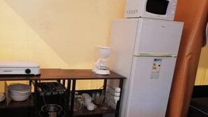 Cocina compacta con microondas, cafetera y un refrigerador pequeño.