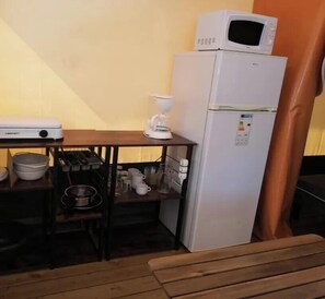 Eine kleine Küche mit Mikrowelle, Kaffeemaschine und einem kleinen Kühlschrank.