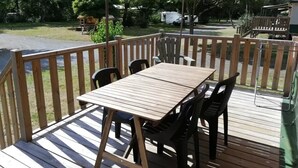 Una terraza al aire libre con una mesa y sillas, rodeada por una barandilla de madera.